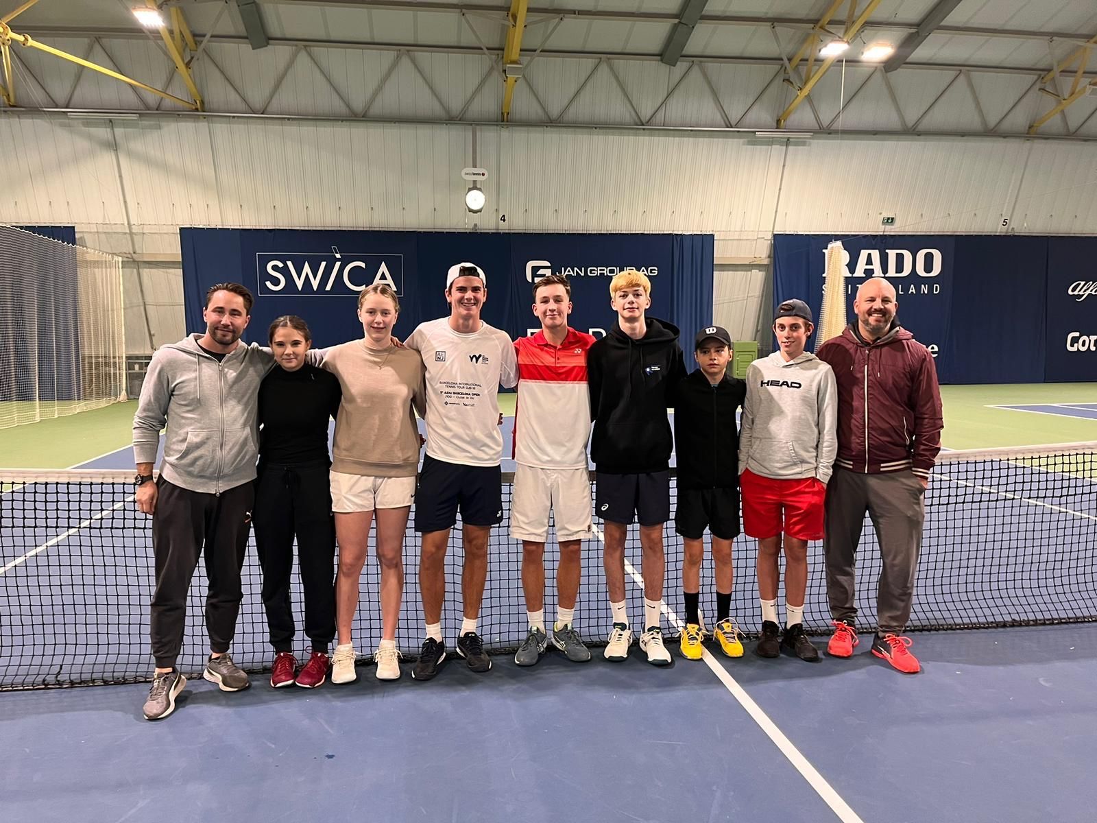 Eine Gruppe von Menschen posiert auf einem Tennisplatz für ein Foto.