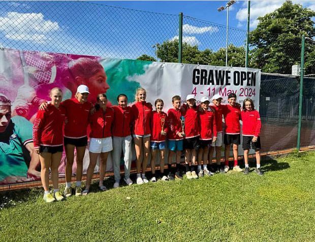 Eine Gruppe von Menschen posiert für ein Foto vor einem Schild mit der Aufschrift „Grawe Open“.