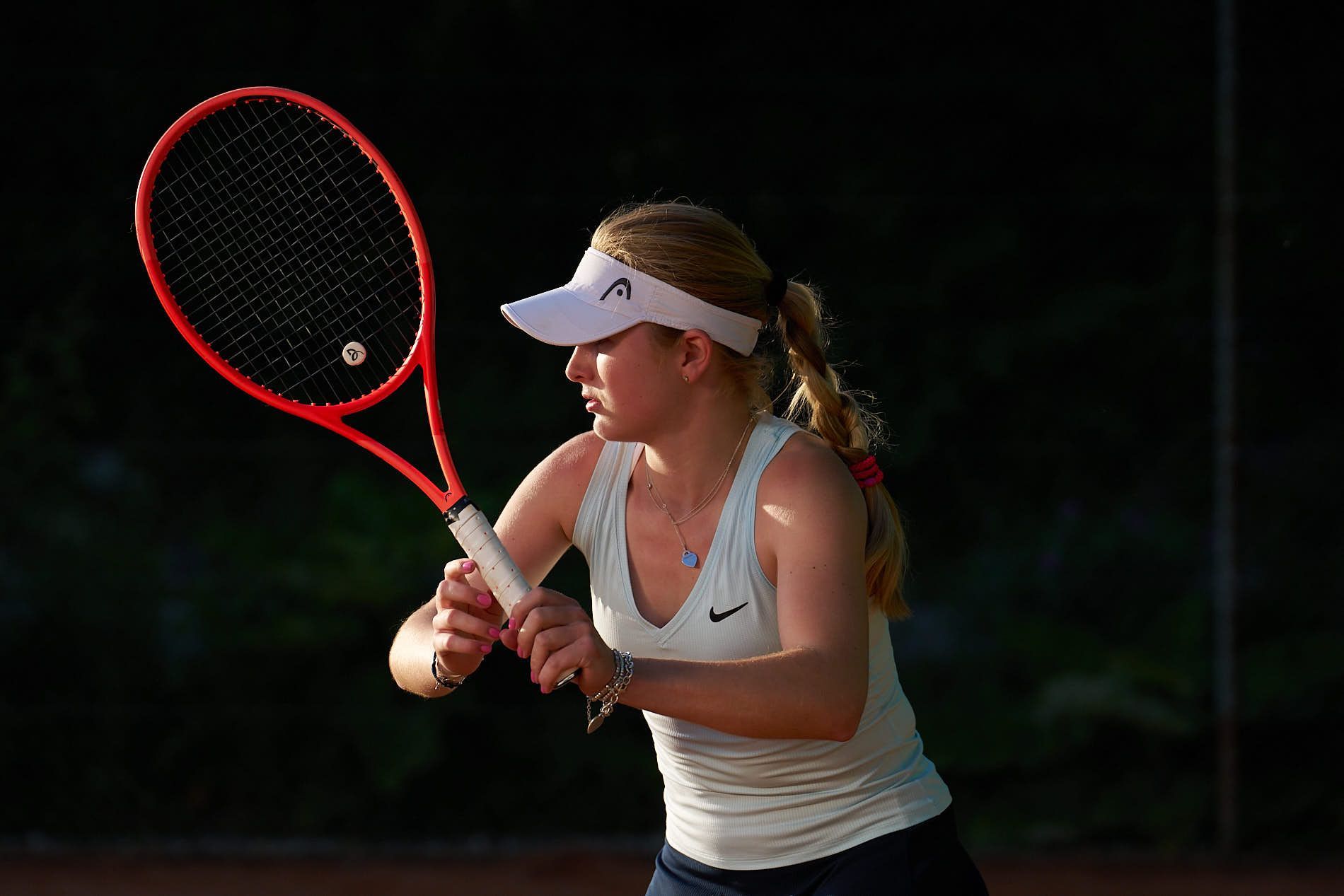 Eine Frau hält auf einem Tennisplatz einen roten Tennisschläger.