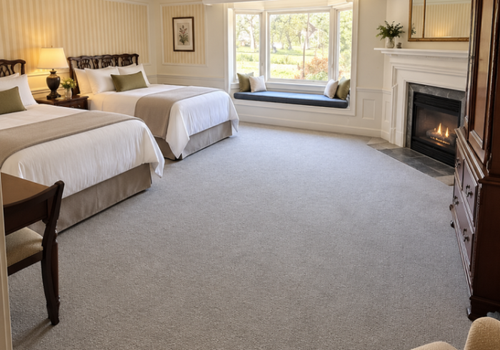 Bright bedroom with two twin beds, large window seat, and fireplace on the right