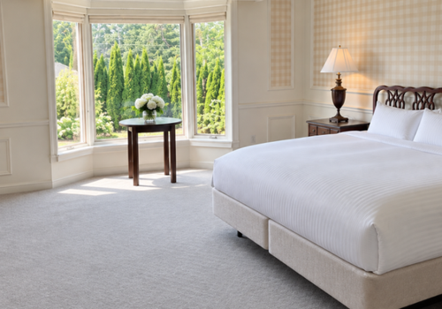Bright bedroom with a bed, bay window, small table, and garden view