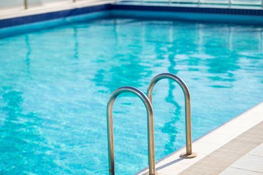Swimming pool with blue water and silver ladder.