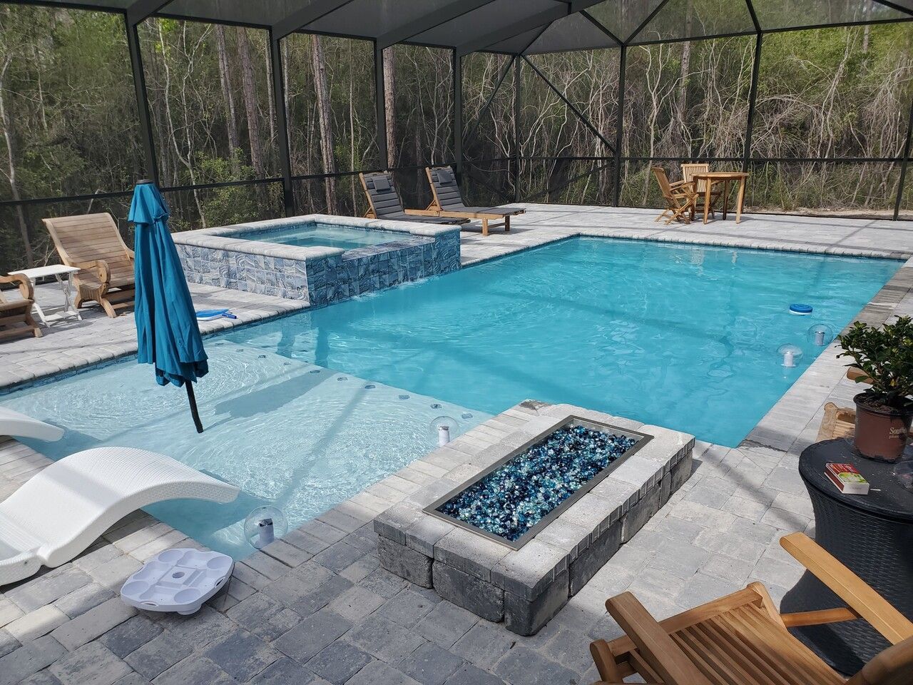 Luxury backyard pool with lounge chairs, tropical landscaping, and a two-story house in the background
