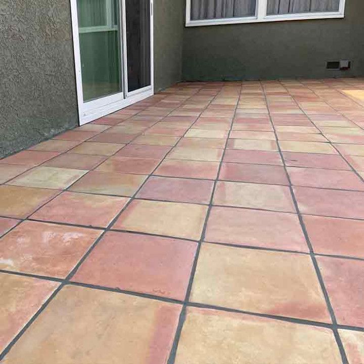 Terracotta-tiled patio beside a house with sliding glass doors and a window