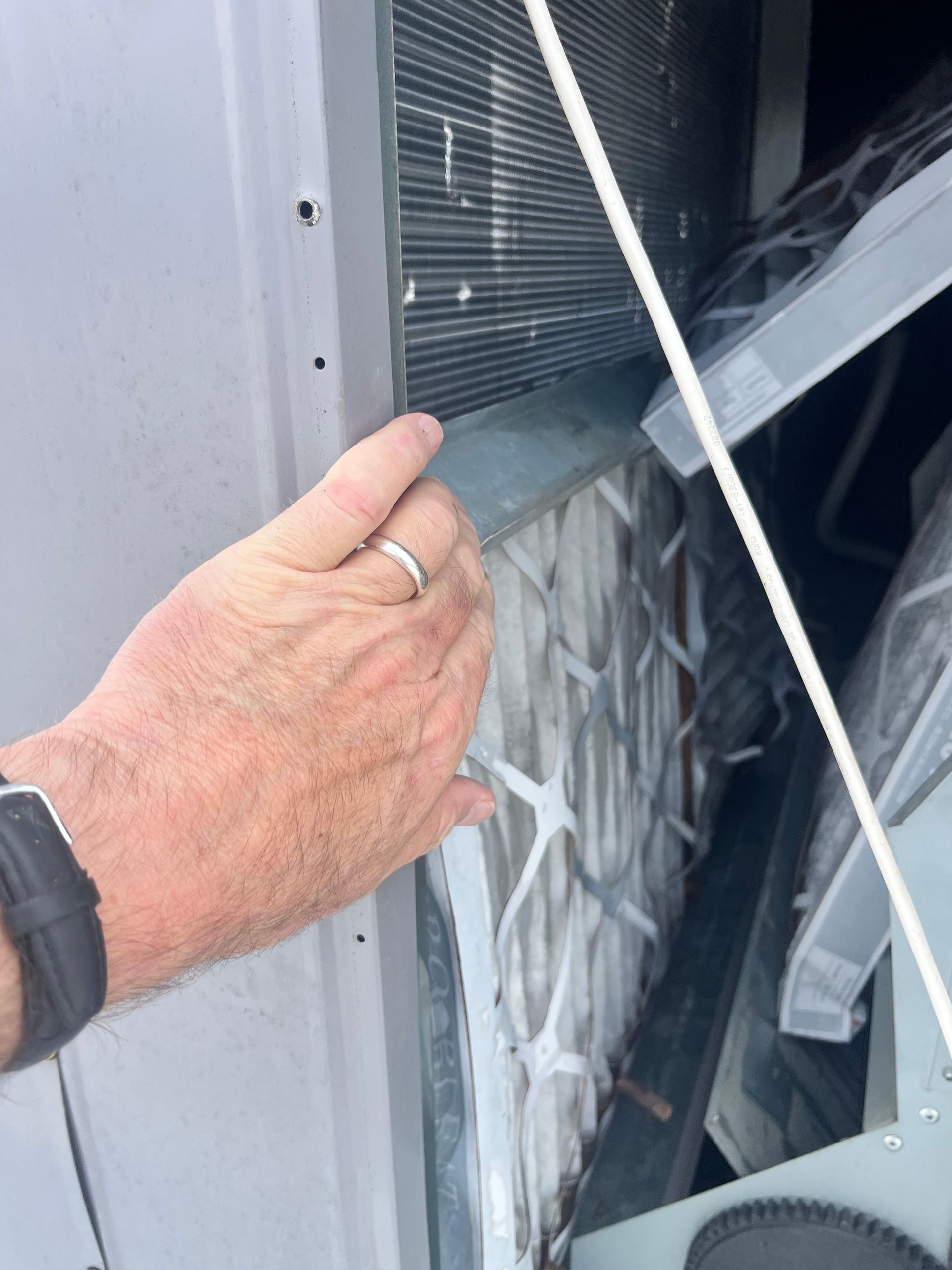 Two HVAC technicians inspecting an outdoor air conditioning unit. One writes on a clipboard, the other holds a tool.