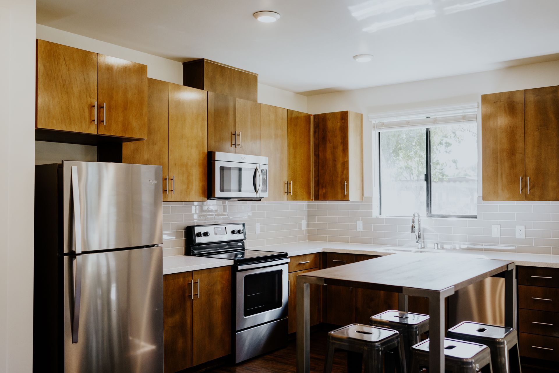 An empty kitchen with stainless steel appliances and wooden cabinets