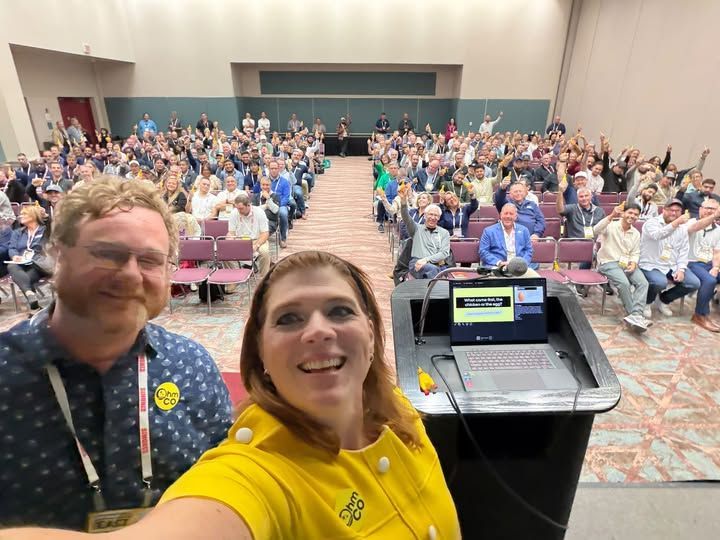 Mike and Mel Ohlinger taking a selfie in front of a packed audience at CarwashCon East