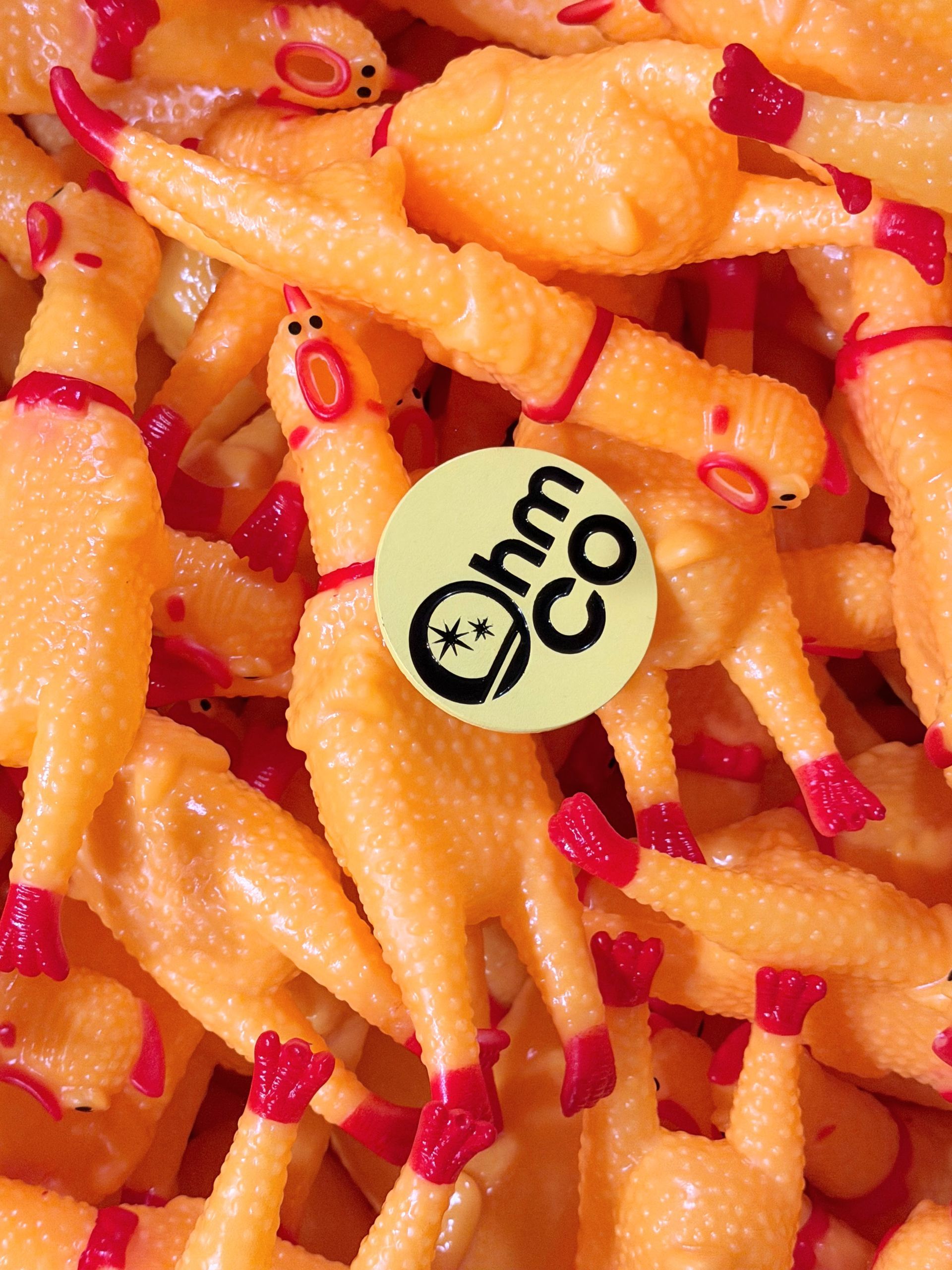 A pile of yellow rubber chickens with an OhmCo pin in the middle