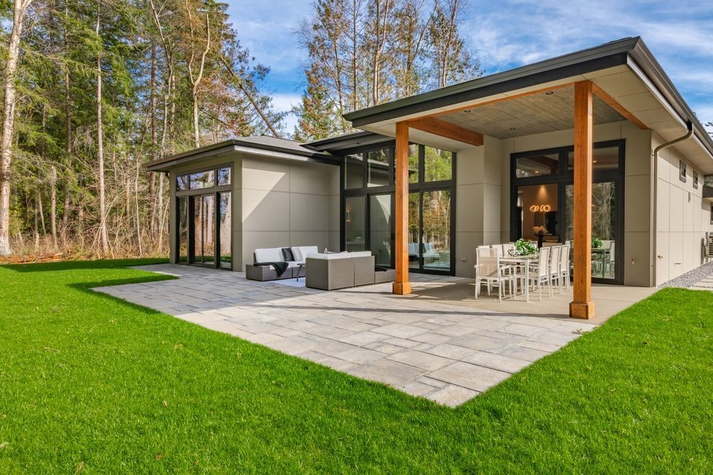 A modern house with a large lawn and a patio in front of it