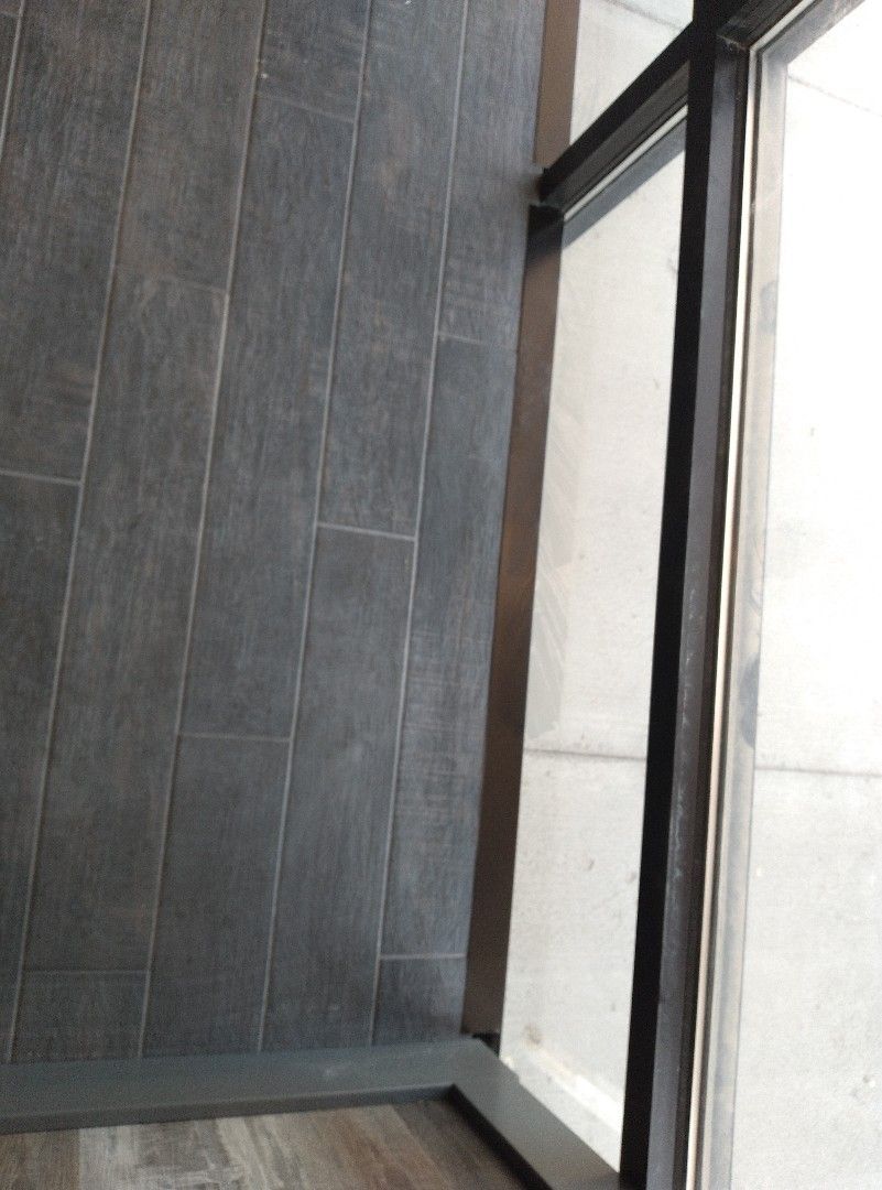 A corner of a room with a window and a tiled floor