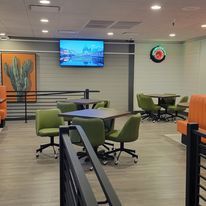 A restaurant with tables and chairs and a flat screen tv on the wall