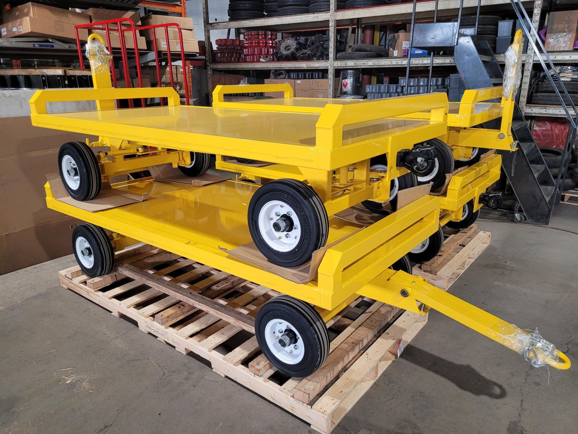 Two yellow carts are stacked on top of each other on a wooden pallet.