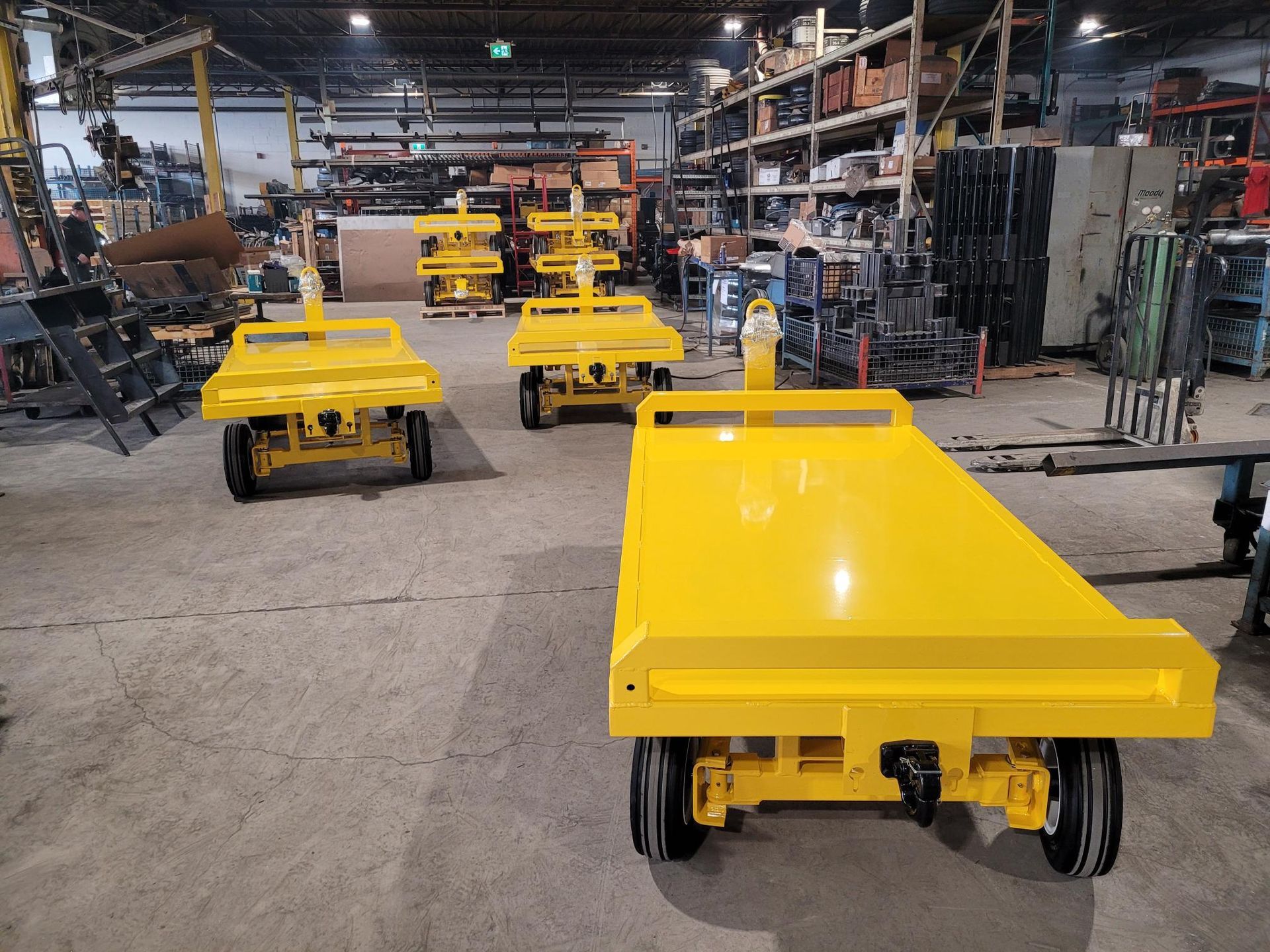 A bunch of yellow carts are sitting in a warehouse.