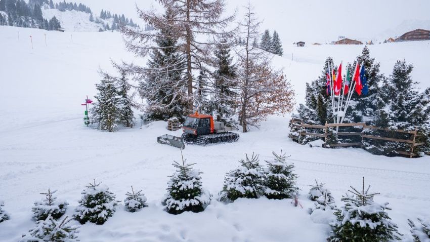 Person viewing the new MTN Equipment website on a laptop with a snow groomer in the background.