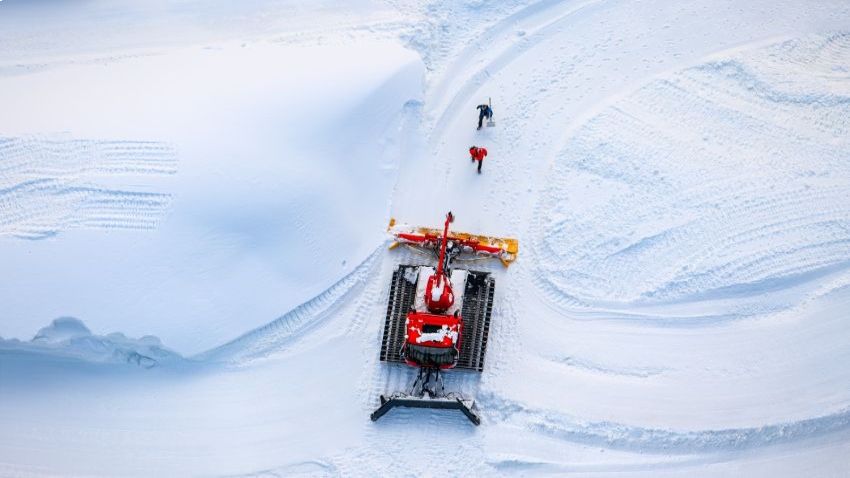 Person viewing the new MTN Equipment website on a laptop with a snow groomer in the background.
