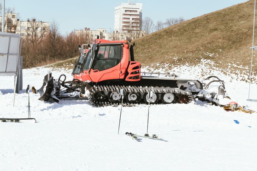 Person viewing the new MTN Equipment website on a laptop with a snow groomer in the background.
