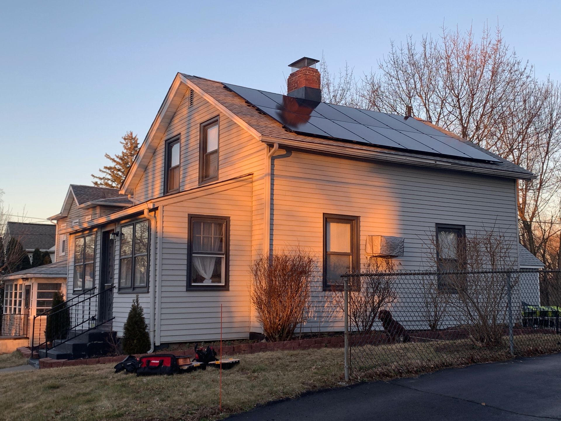 Solar panels mounted on a house roof against a blue sky with clouds