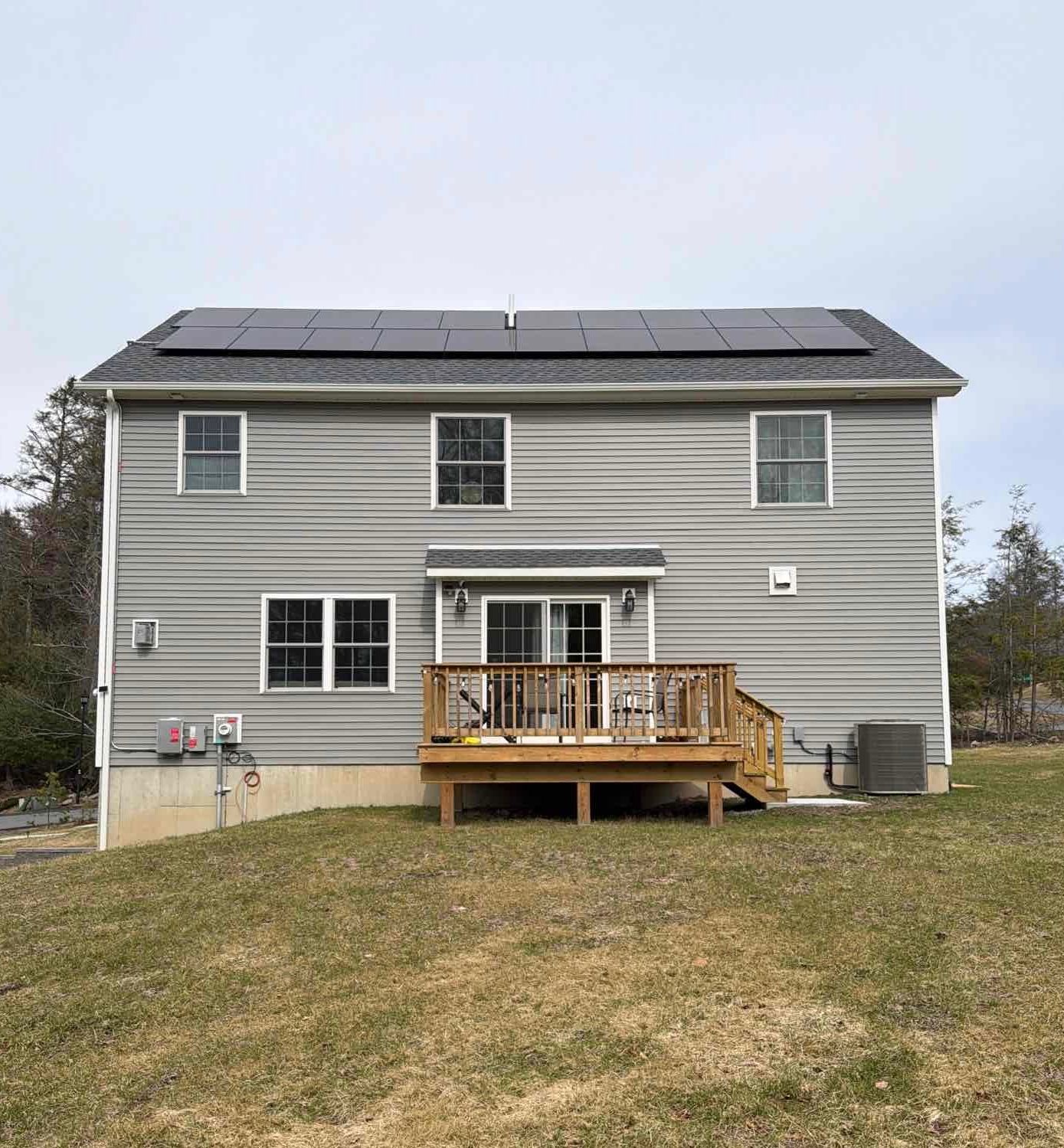 Solar panels installed on a dark roof against a blue sky.