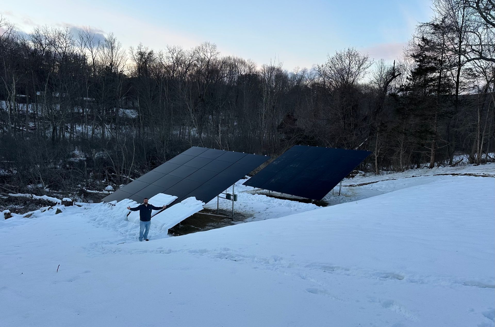 Worker installing solar panels on a roof at sunset