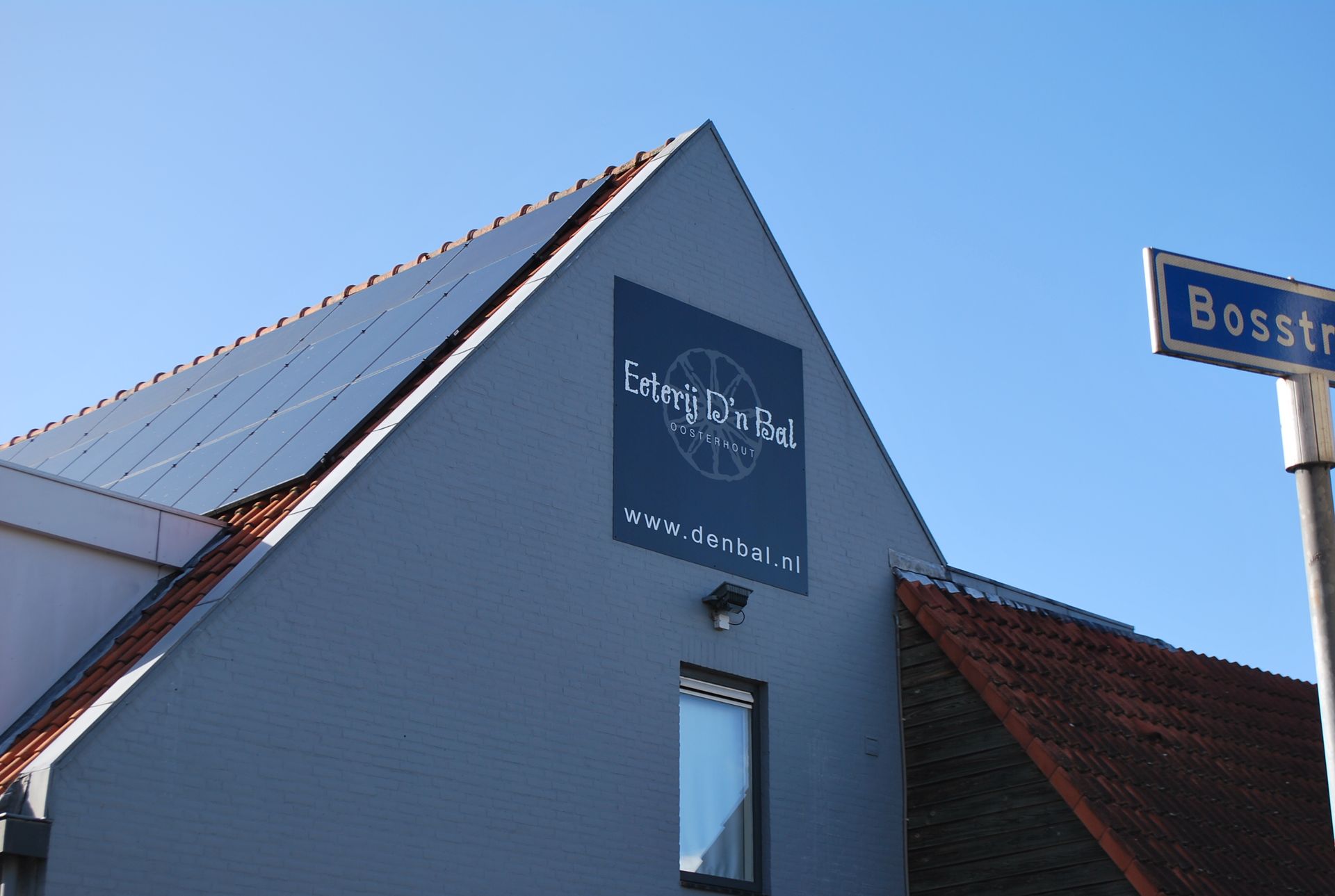 Gebouw met zonnepanelen en een bord met de tekst 