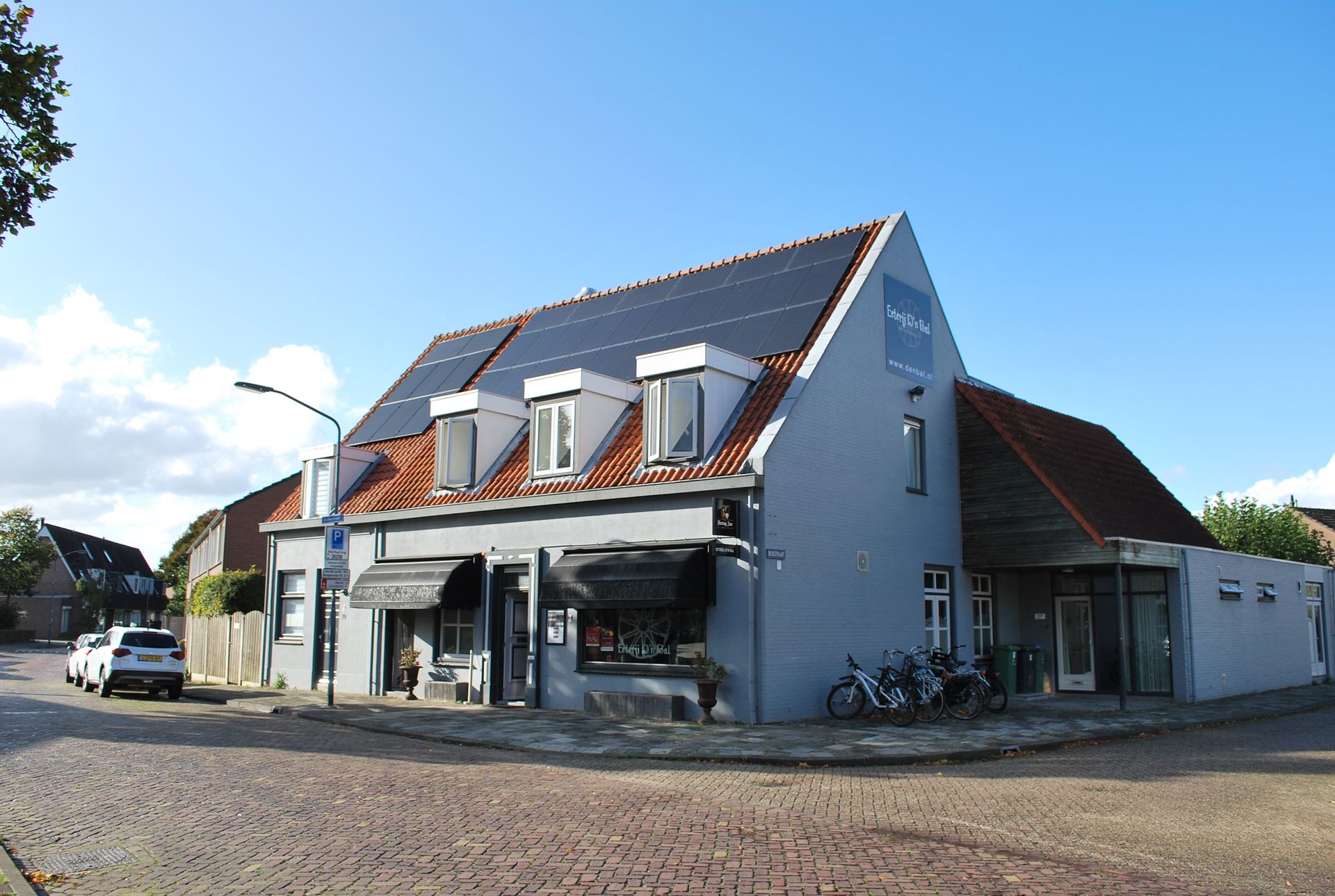 Hoekpand met zonnepanelen, luifel en fietsen die buiten geparkeerd staan.
