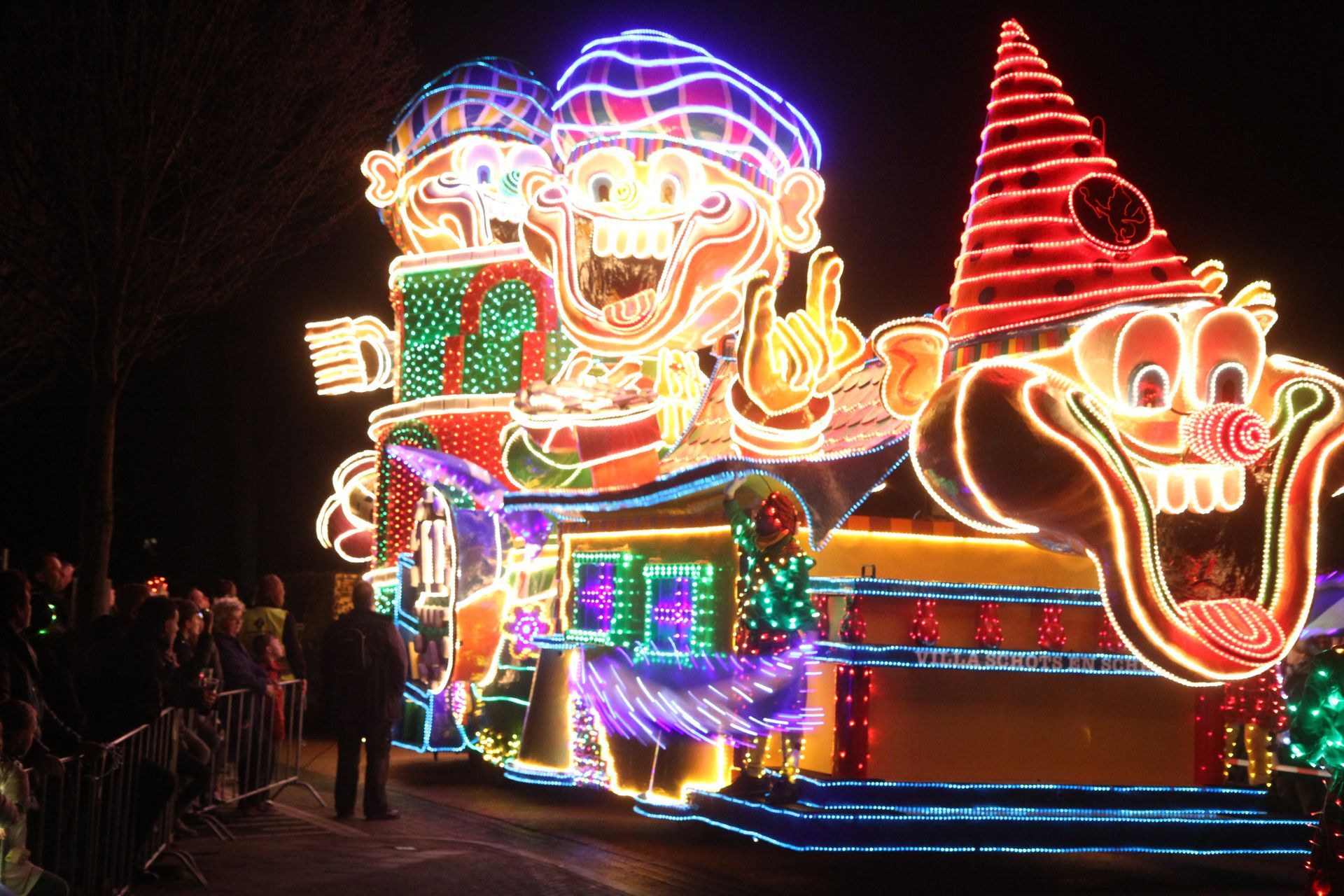 Een oplichtende praalwagen met stripfiguren 's nachts.