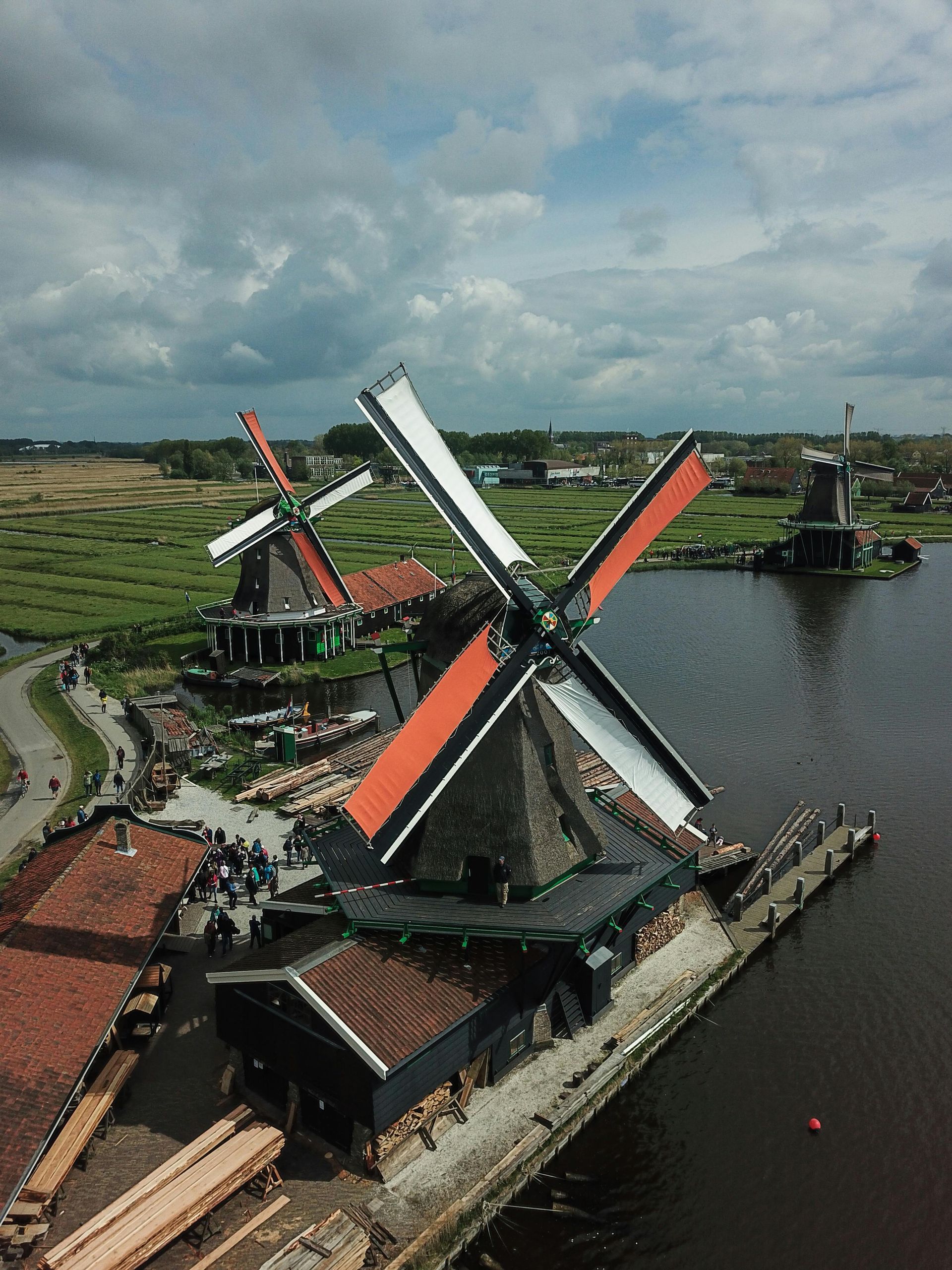 Windmolens met zwarte en oranje wieken aan een kanaal in een Nederlands landschap.