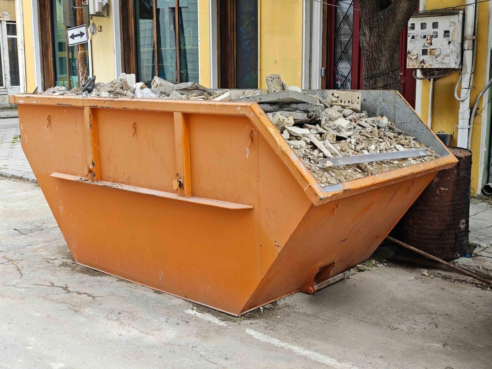 Orange Industrial Dumpster Full of Construction Debris and Rubble on Urban Street. Orange Industrial Dumpster Full of Construction Debris and Rubble on Urban Street.