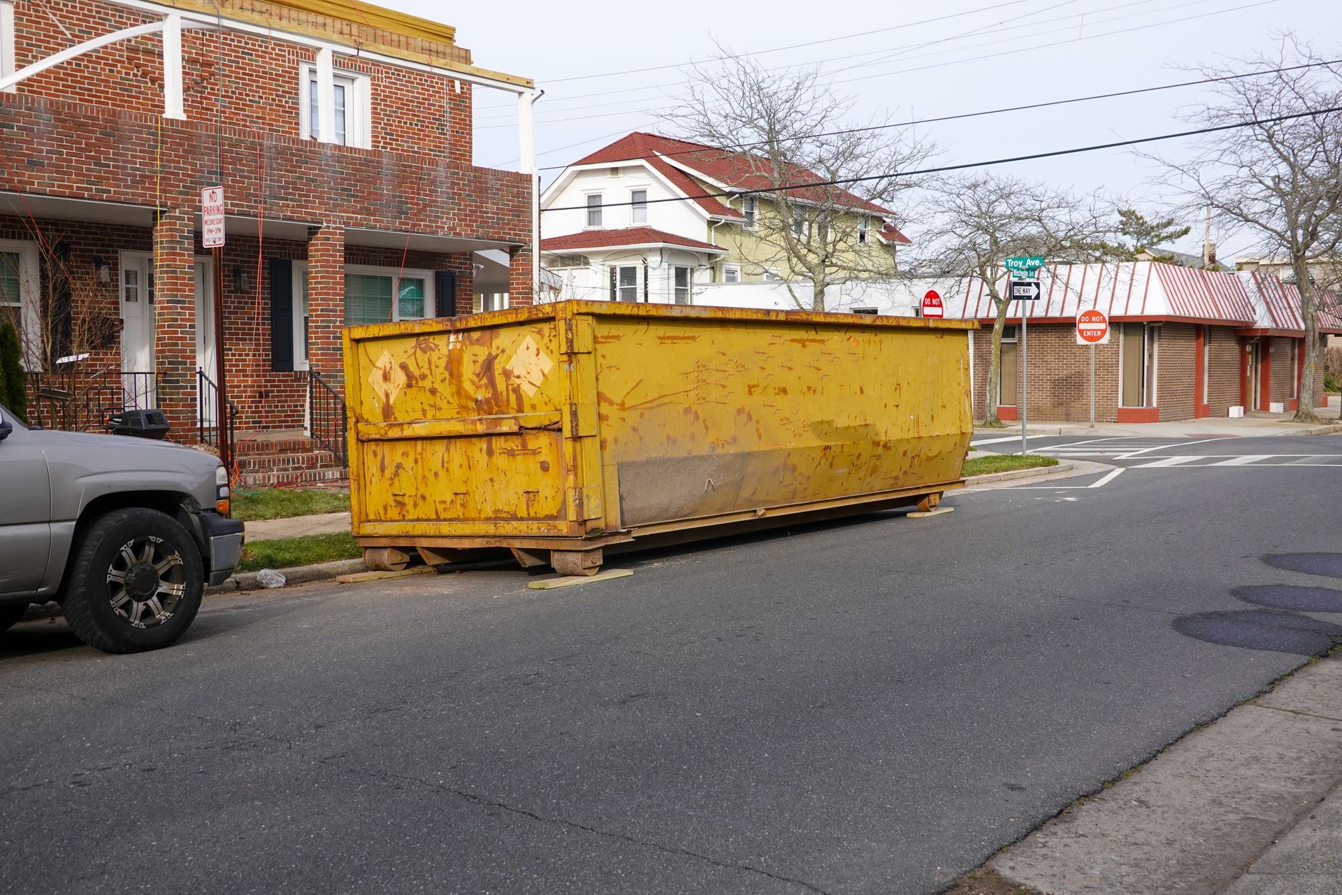 A yellow dumpster in front of a brick building under renovation, showcasing dumpster rental.