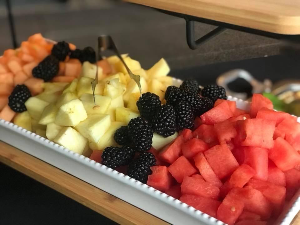 Fruit tray with watermelon, pineapple, oranges, blackberries, and melon cubes on a counter