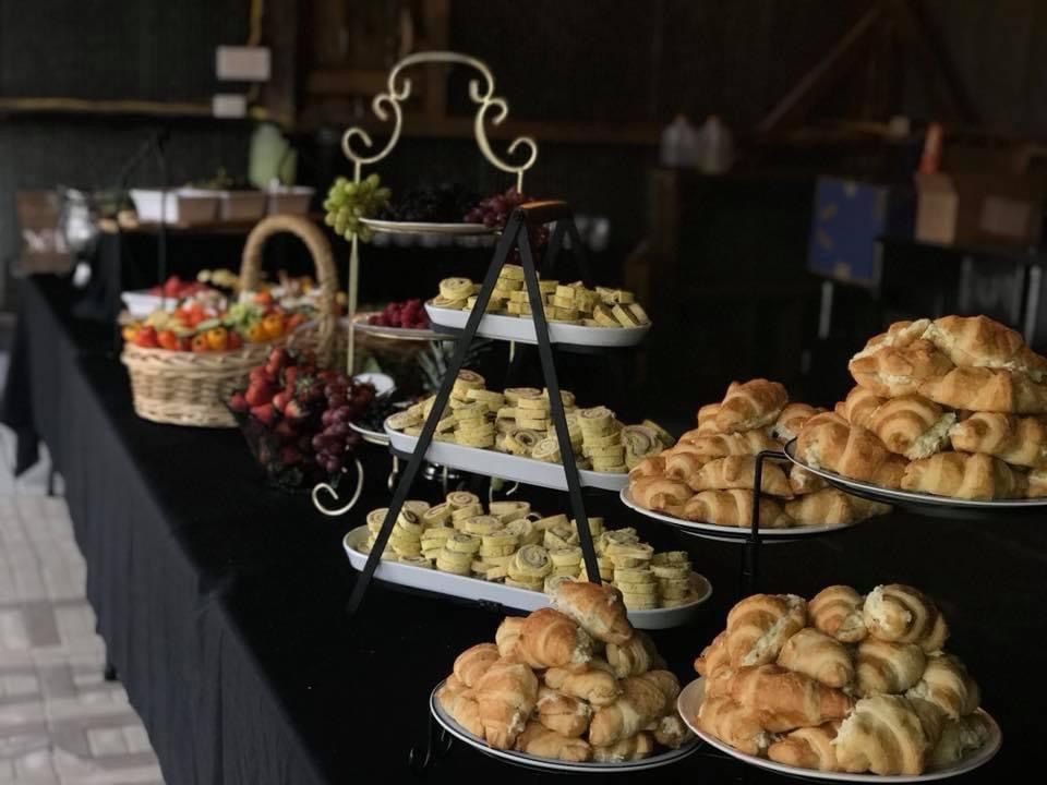 Pastry buffet with croissants, muffins and fruit baskets on tiered stands in a dim room
