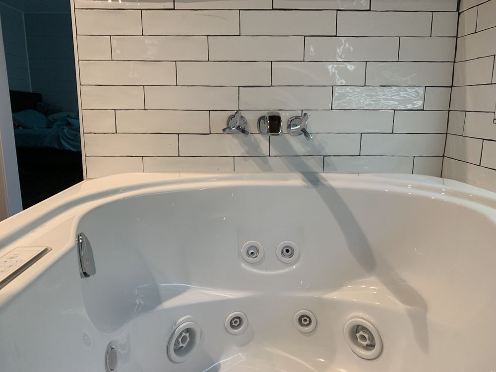 a white jacuzzi tub in a bathroom next to a white brick wall .