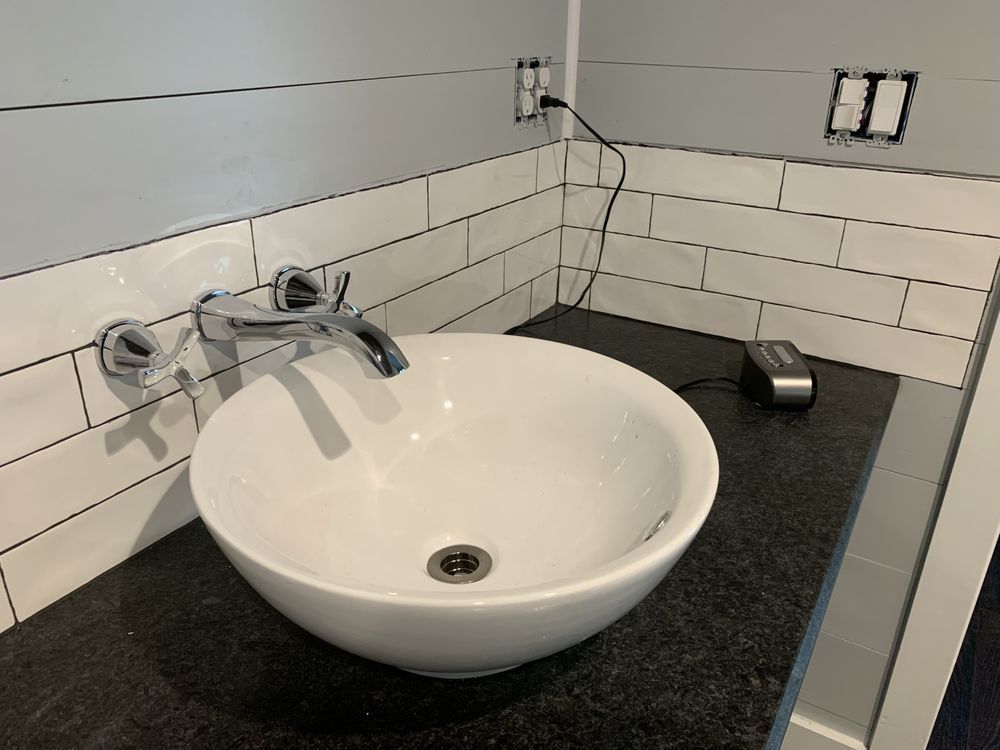 a white sink is sitting on a black counter in a bathroom .