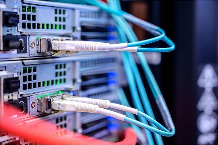 Close-up of network server hardware with blue fiber optic cables connected to ports in a data center rack.