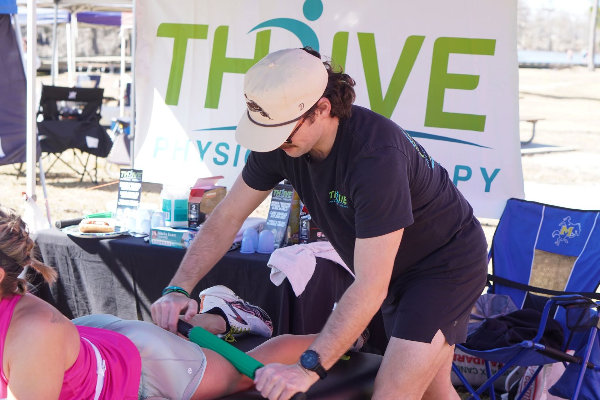 Person giving aid to someone on a stretcher at an outdoor Thrive event booth