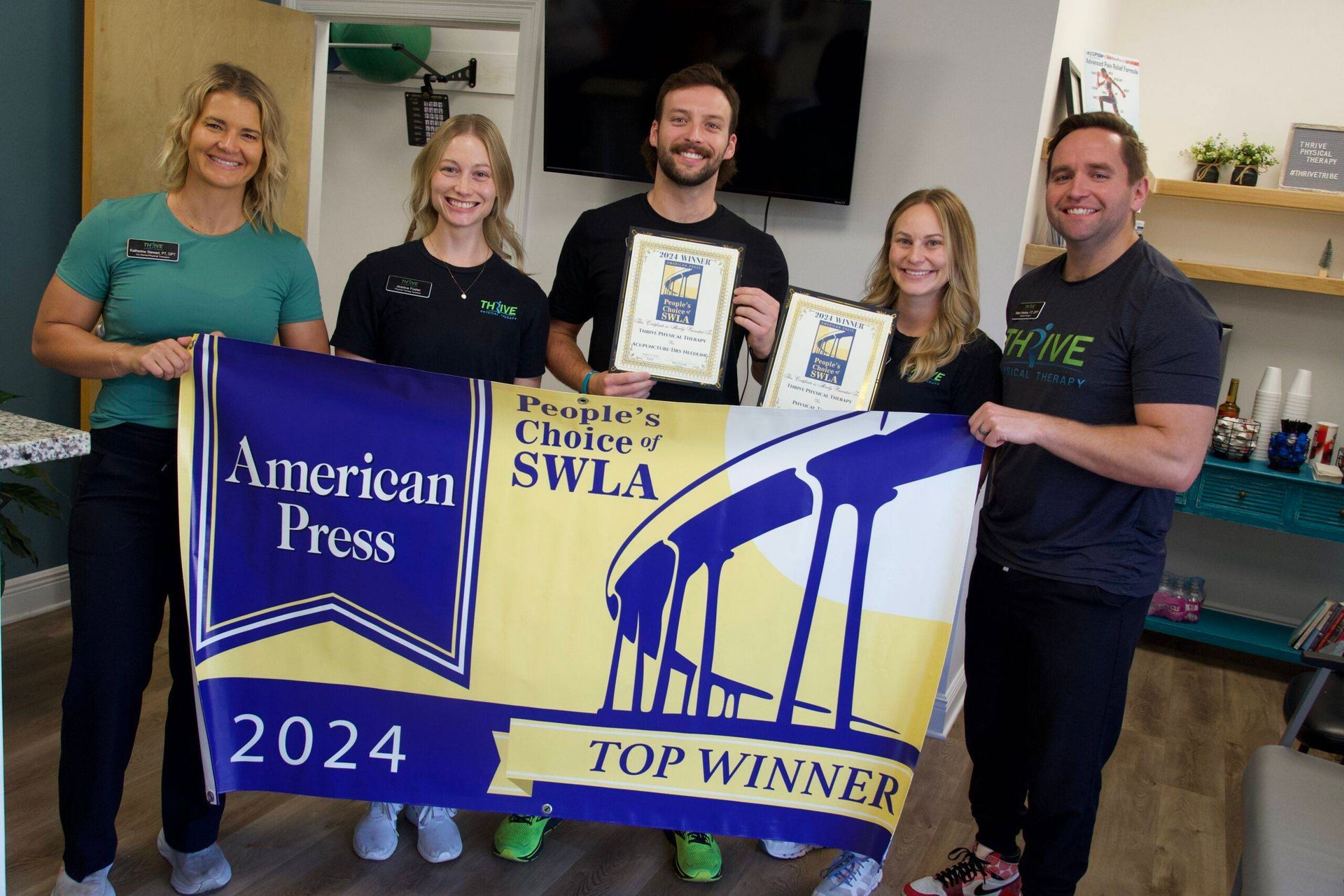 Five people hold an American Press 2024 Top Winner banner and award plaque indoors.
