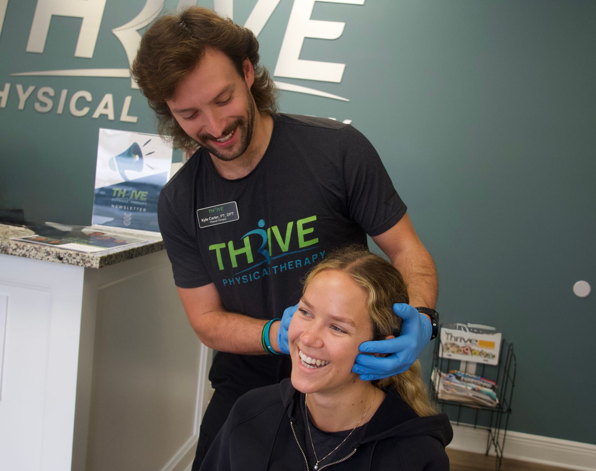 Smiling person gets a neck massage from a clinician in a Thrive Physical Therapy office