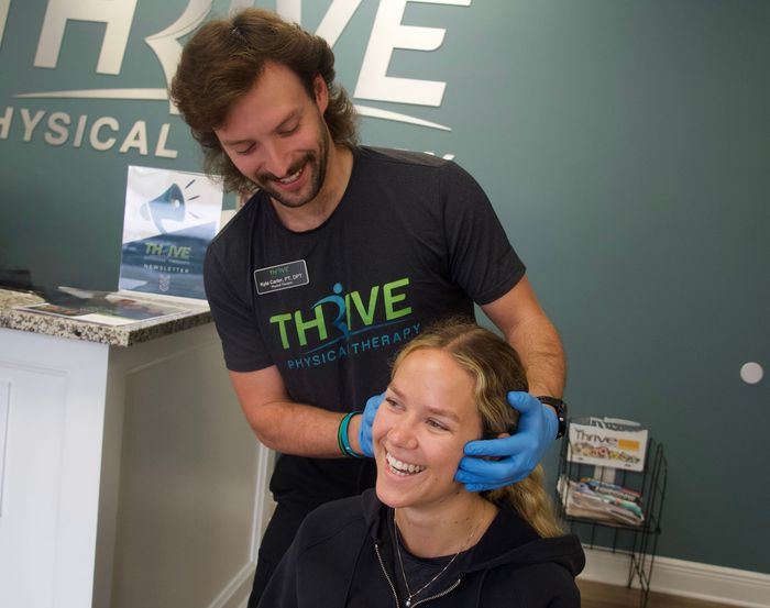 Smiling person gets a neck massage from a clinician in a Thrive Physical Therapy office