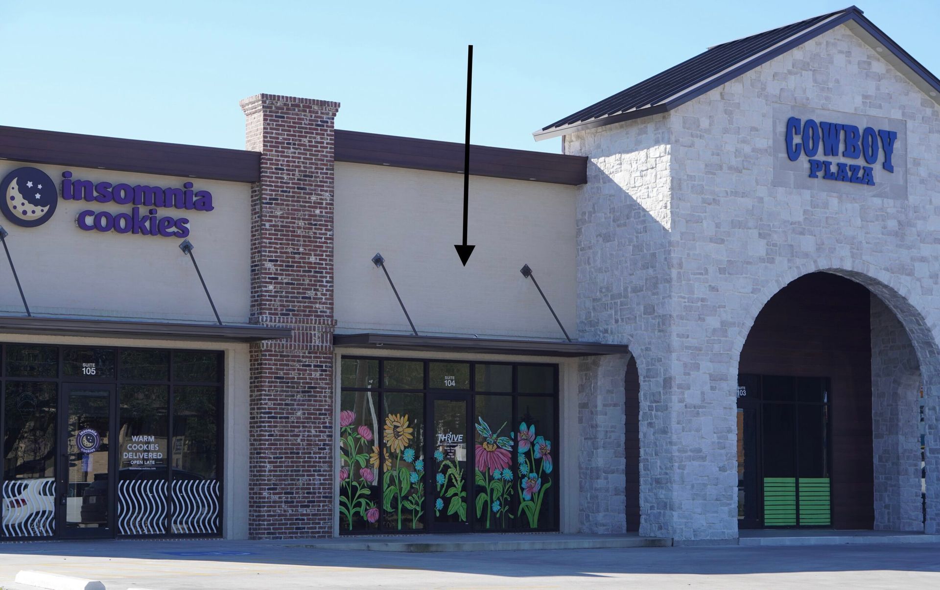 Storefront with “Infonita College” sign, stone facade, and arched entrance in a shopping center