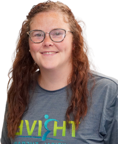 Smiling person with glasses and long red hair wearing a gray T-shirt with a colorful logo