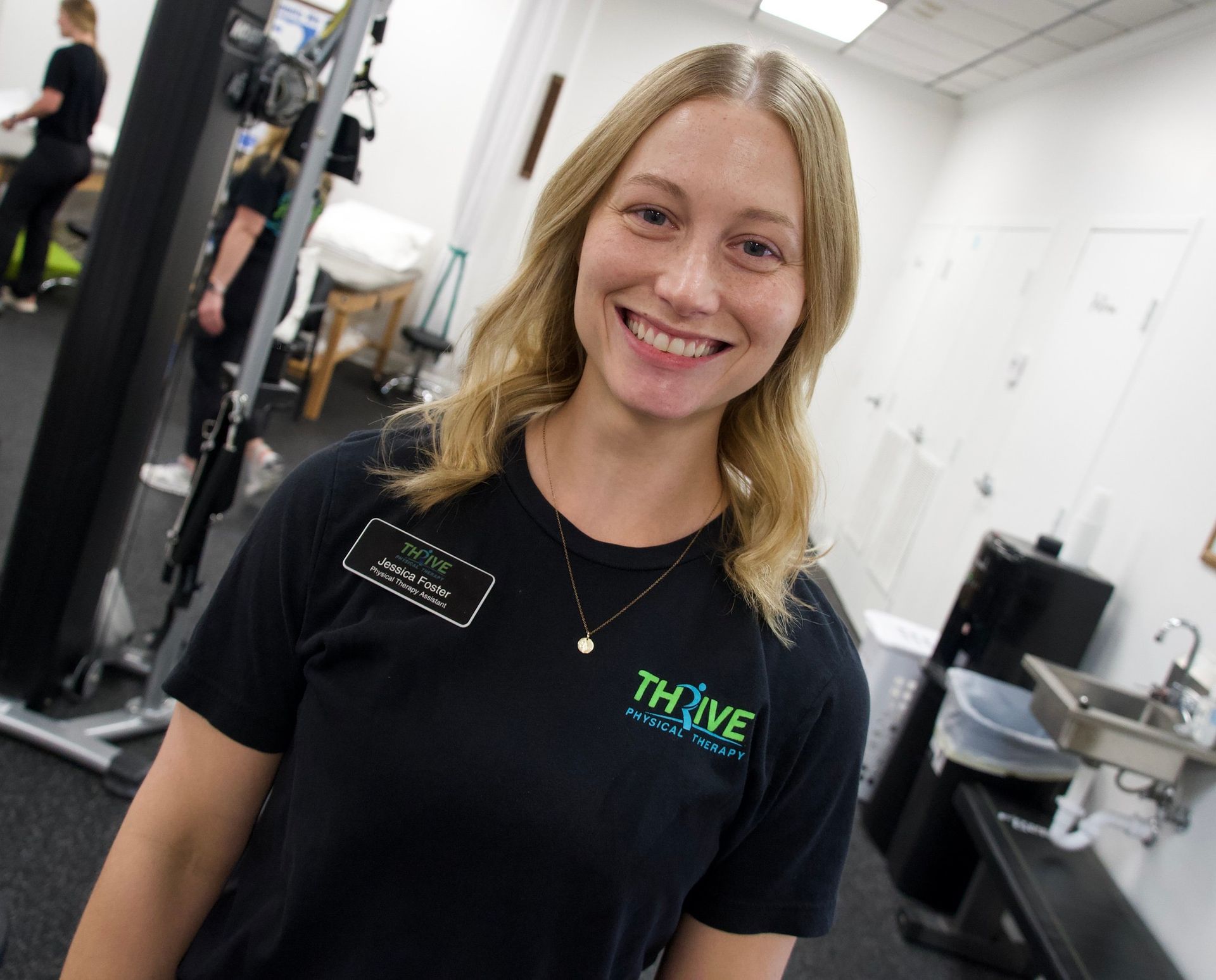 Smiling employee in black T-shirt standing in a bright office or salon space