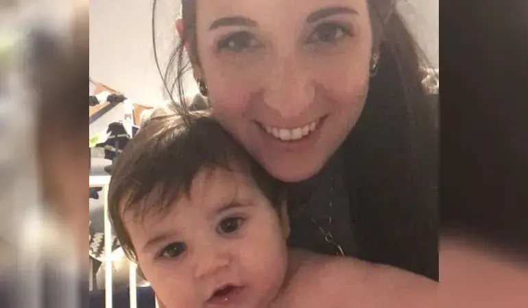 Smiling woman holding a baby close to the camera indoors