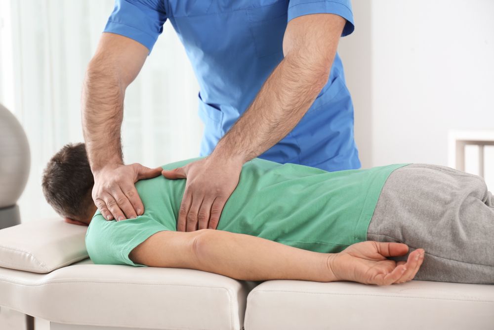 Therapist performing back massage on a person lying face down on a treatment table