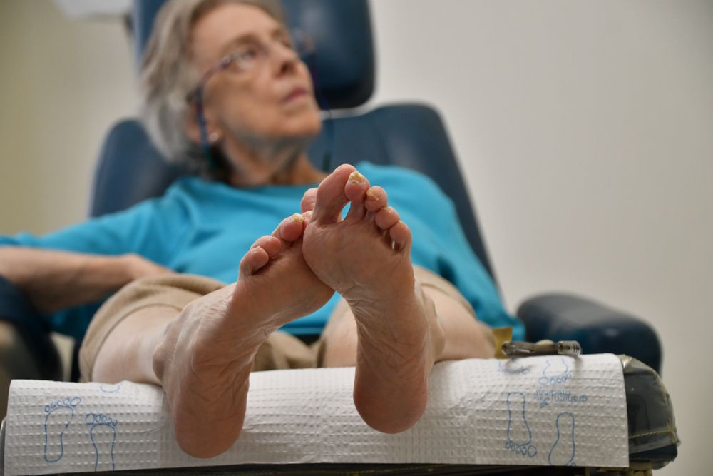 Person reclines on a bed with feet raised, wearing a blue shirt in a cozy indoor setting