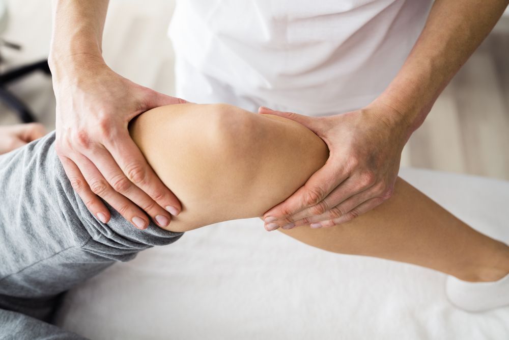 Physical therapist massaging a patient’s bent leg on a treatment table