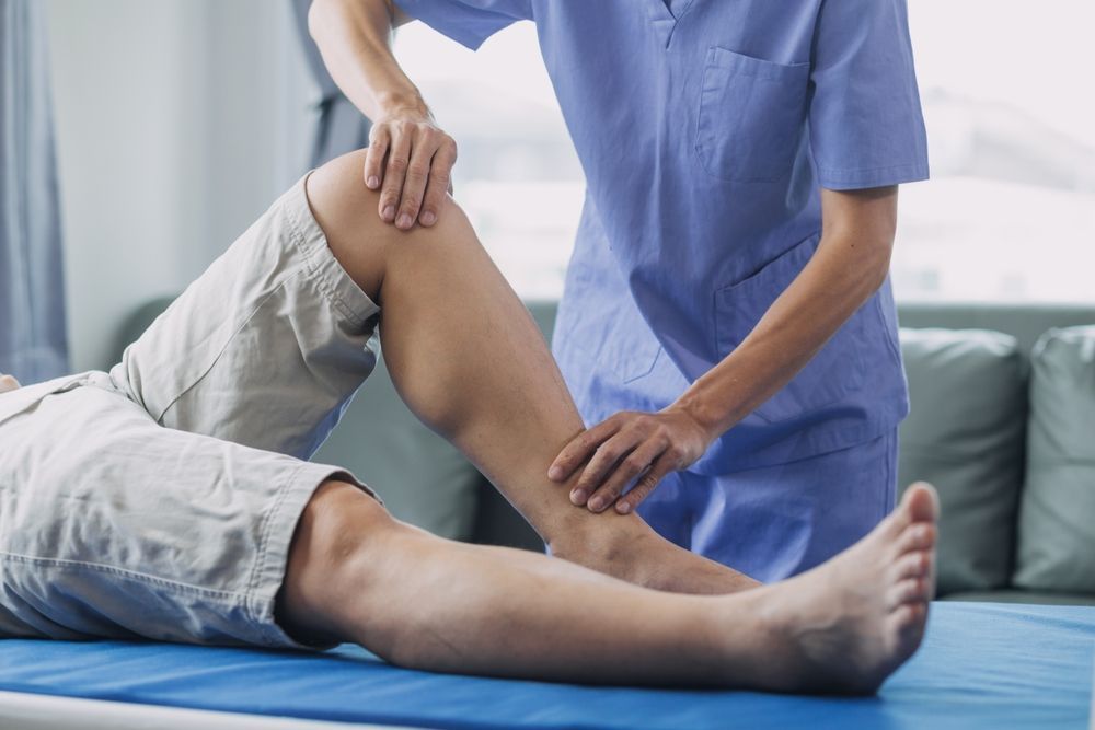 Physical therapist examining a patient’s knee on a treatment table in a clinic