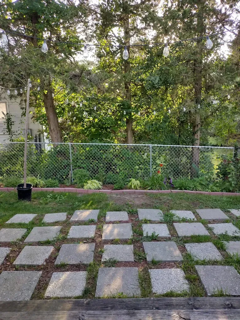 Backyard patio with square pavers, chain-link fence, and trees in the background