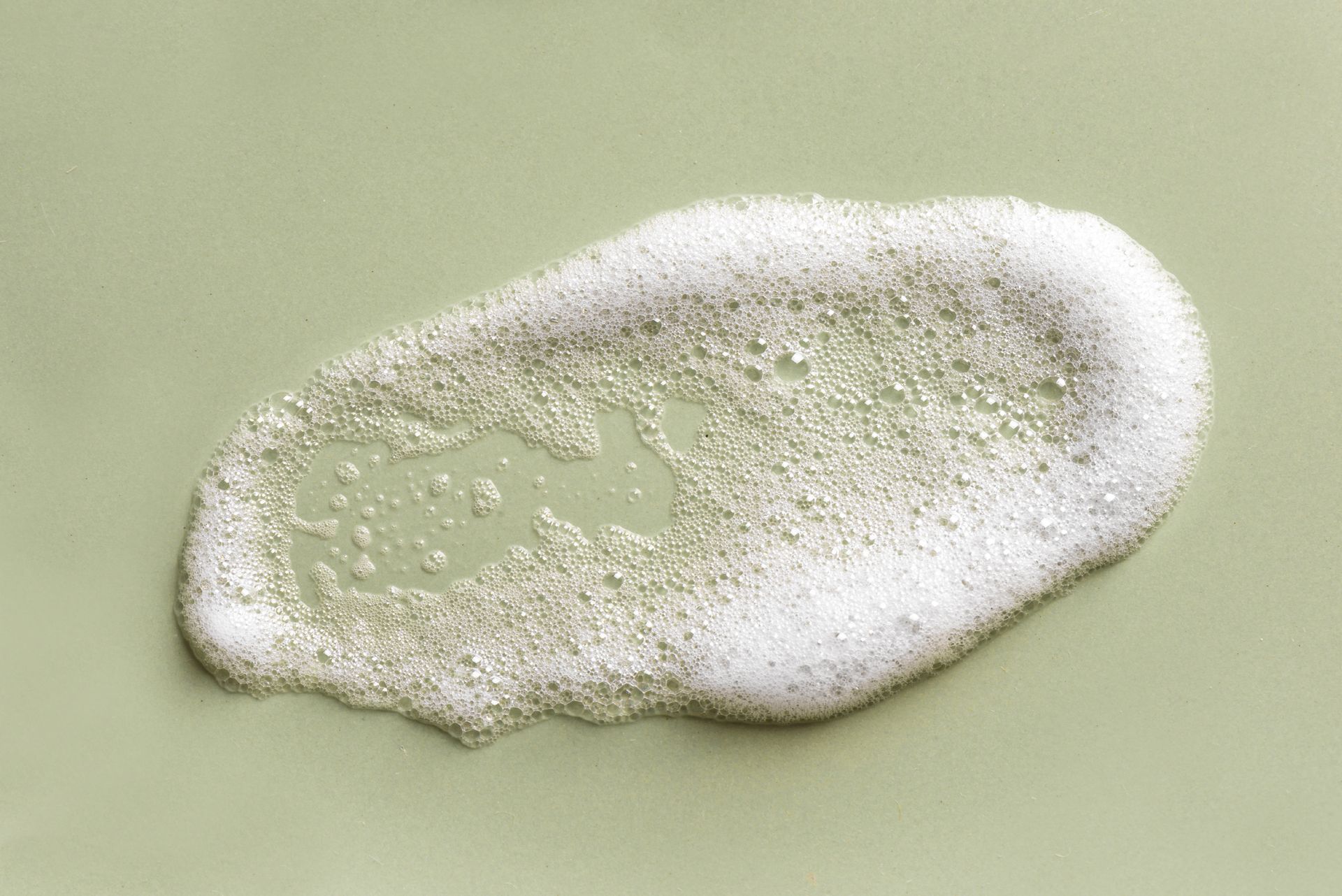 A bottle of foaming cleanser next to a box on a table.
