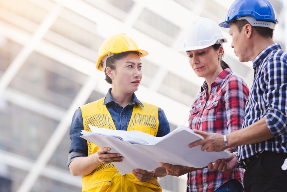 Three Construction Workers in Hard Hats Reviewing Blueprints at a Building Site — Tick of Approval Pty Ltd in Berrimah, NT