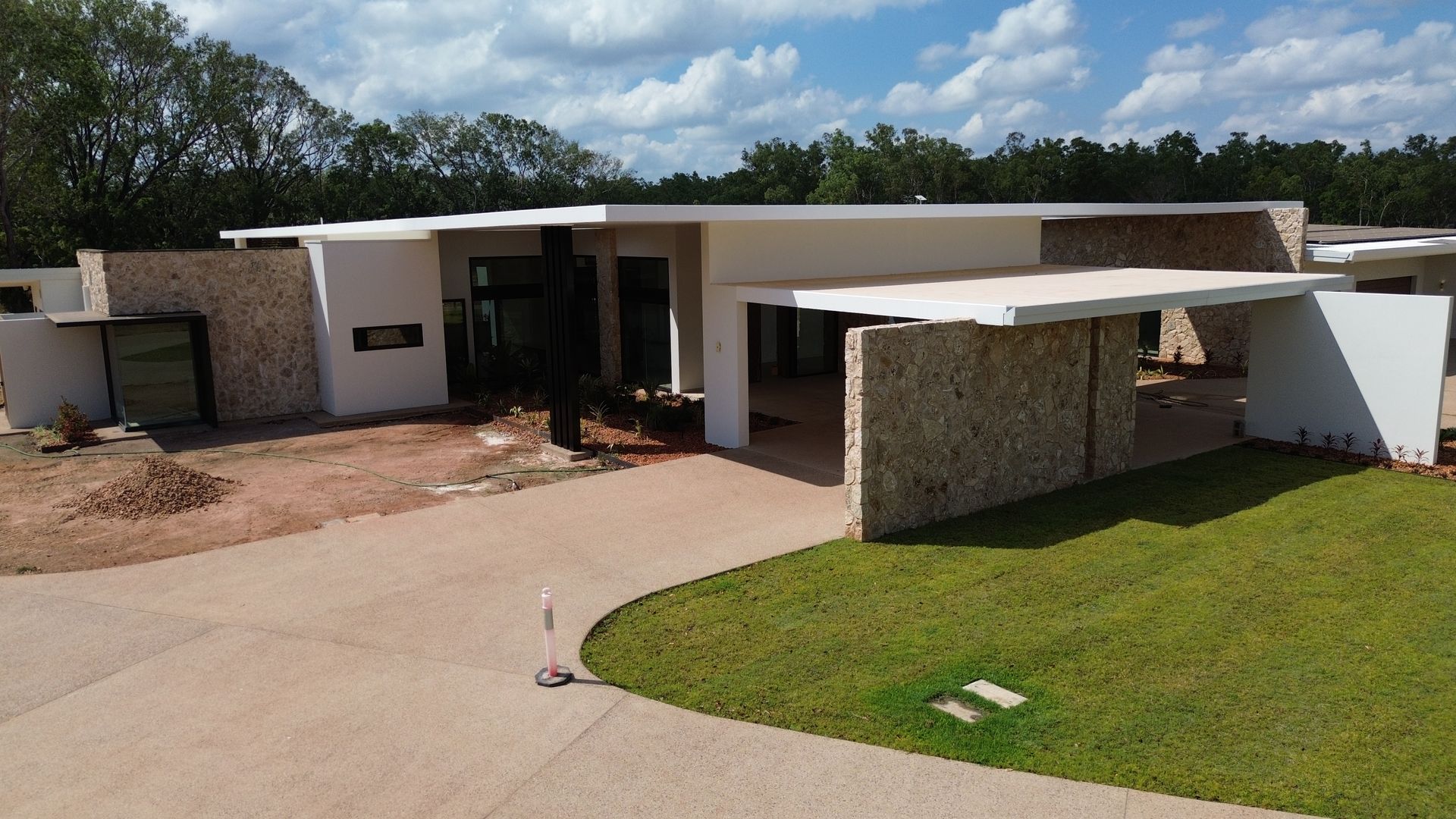 Modern single-story house with a curved driveway, white walls, stone accents, and a green lawn. — Tick of Approval Pty Ltd in Berrimah, NT
